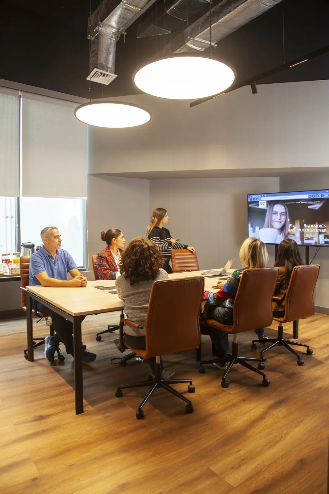 Equipo en videollamada en una sala con pantalla y sillones